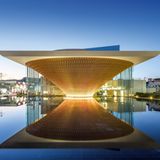 Ein trichterförmiges Gebäude spiegelt sich im Wasser