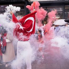 Fans der Türkei feiern ausgelassen auf der Straße mit Flaggen und Rauch.