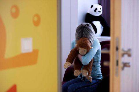 Eine junge Frau sitzt mit einem Kuscheltier im Arm, Symbolfoto Kindesmissbrauch