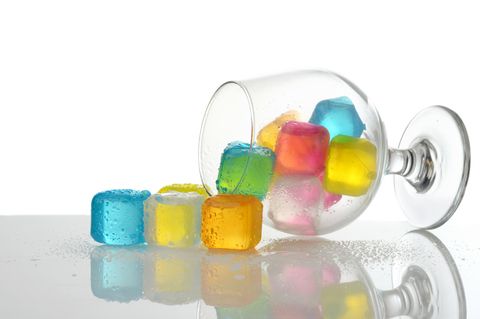 Verschüttete farbige Plastikeiswürfel in Brandyglas