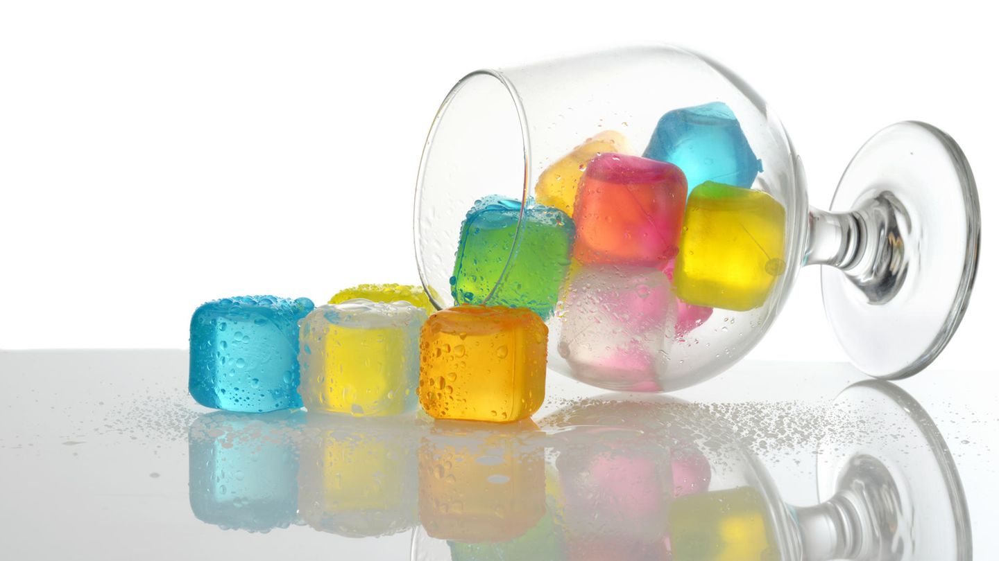 Verschüttete farbige Plastikeiswürfel in Brandyglas