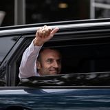 Präsident Emmanuel Macron hebt den Daumen aus seinem Auto