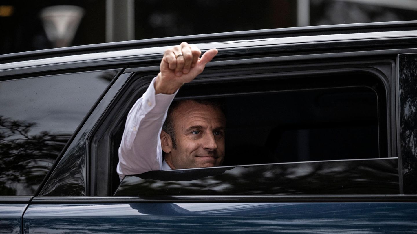 Präsident Emmanuel Macron hebt den Daumen aus seinem Auto