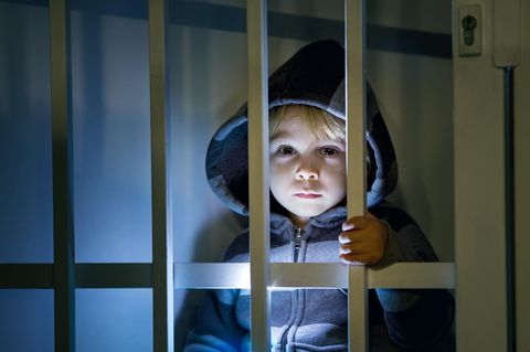 Ein kleines Kind schaut durch die Gitterstäbe in einem Gefängnis