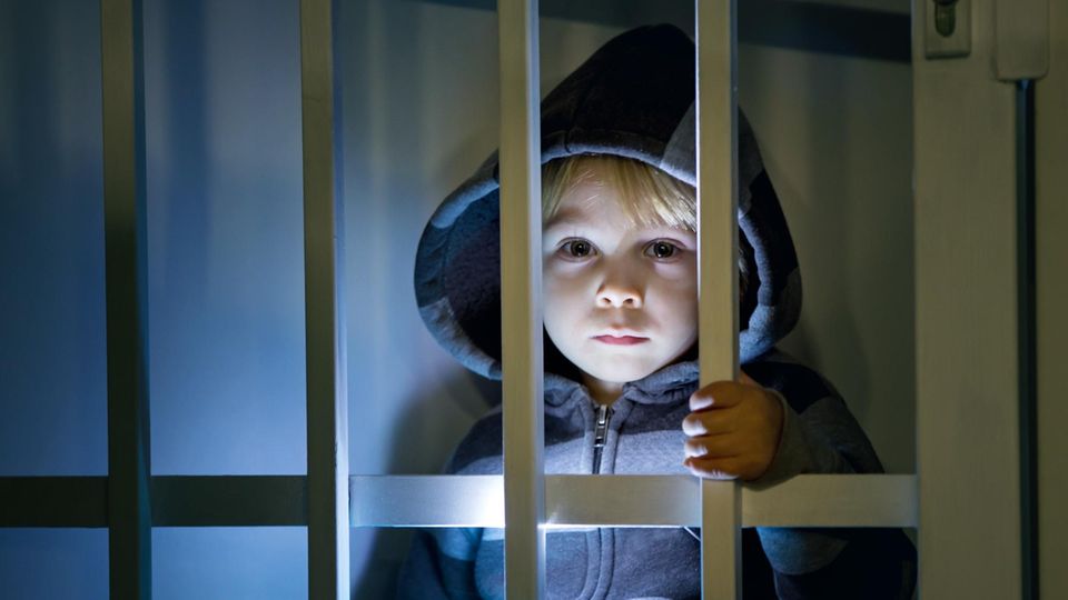 Ein kleines Kind schaut durch die Gitterstäbe in einem Gefängnis