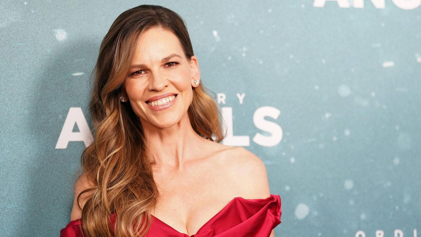 Hillary Swank, eine Frau in einem schicken Kleid, lächelt in die Kamera