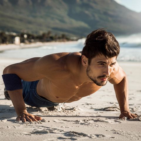 Ein Mann macht Planks am Strand
