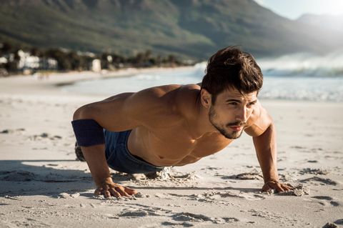 Ein Mann macht Planks am Strand
