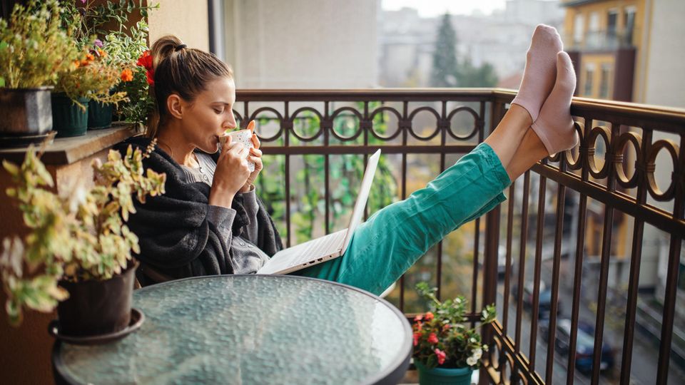 Frau arbeitet im Homeoffice mit Laptop auf dem Balkon