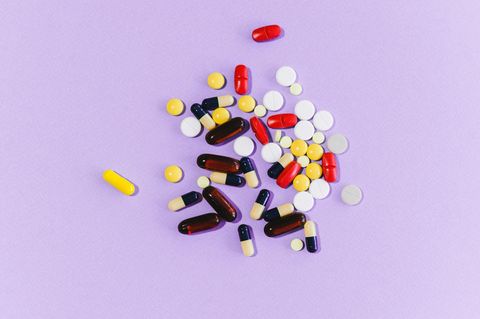 Medikationsfehler: Viele verschiedene Tabletten liegen auf einem lilafarbenen Untergrund