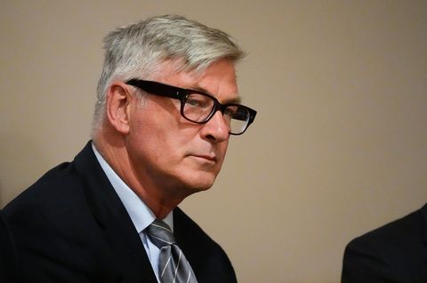 Alec Baldwin trägt eine Brille mit dickem Rahmen. Er hat graue Haare und schaut ernst