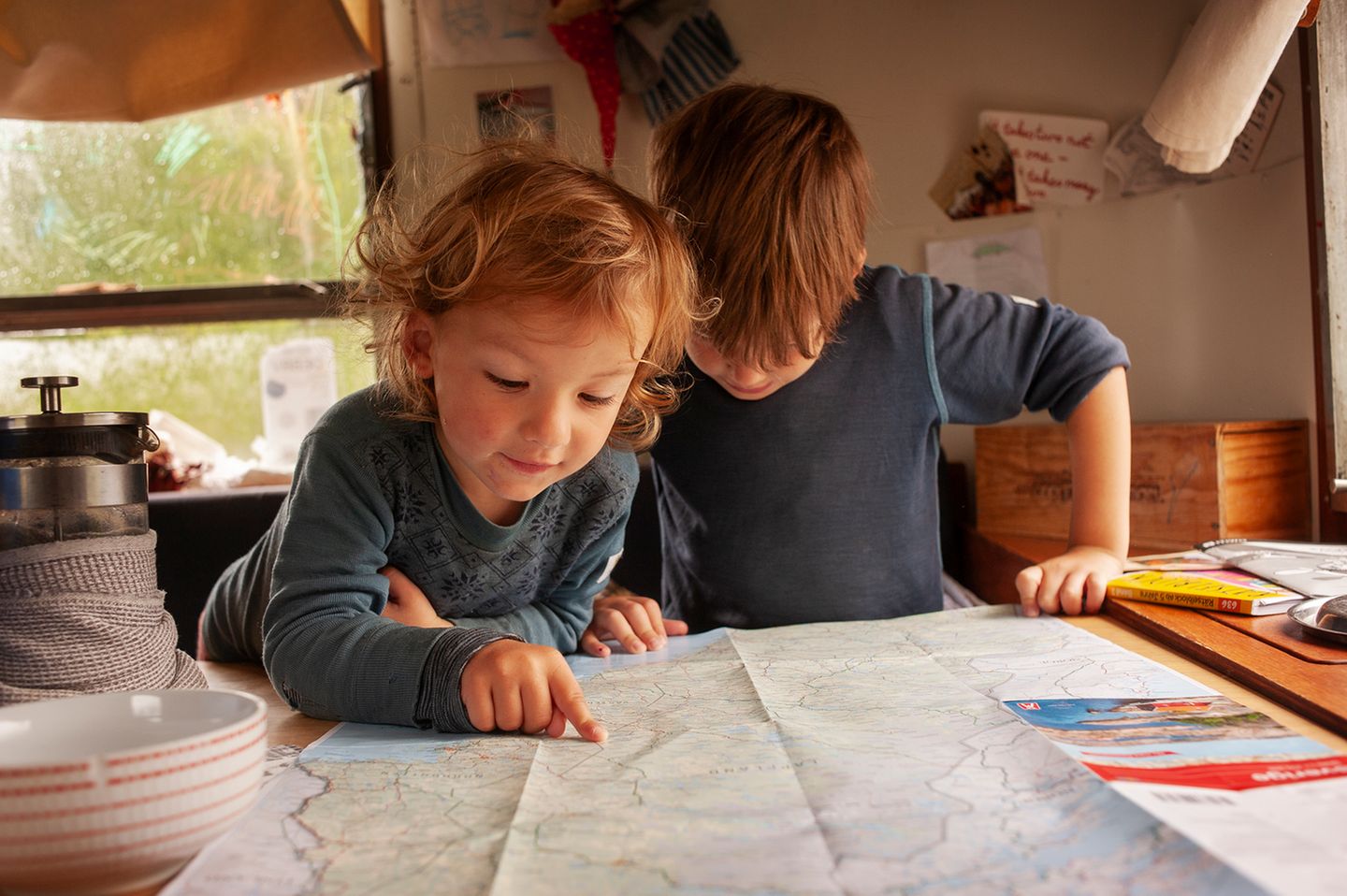 Die beiden Jungs blicken am Tisch im Airstream auf eine Karte von Norwegen