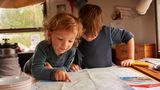 Die beiden Jungs blicken am Tisch im Airstream auf eine Karte von Norwegen