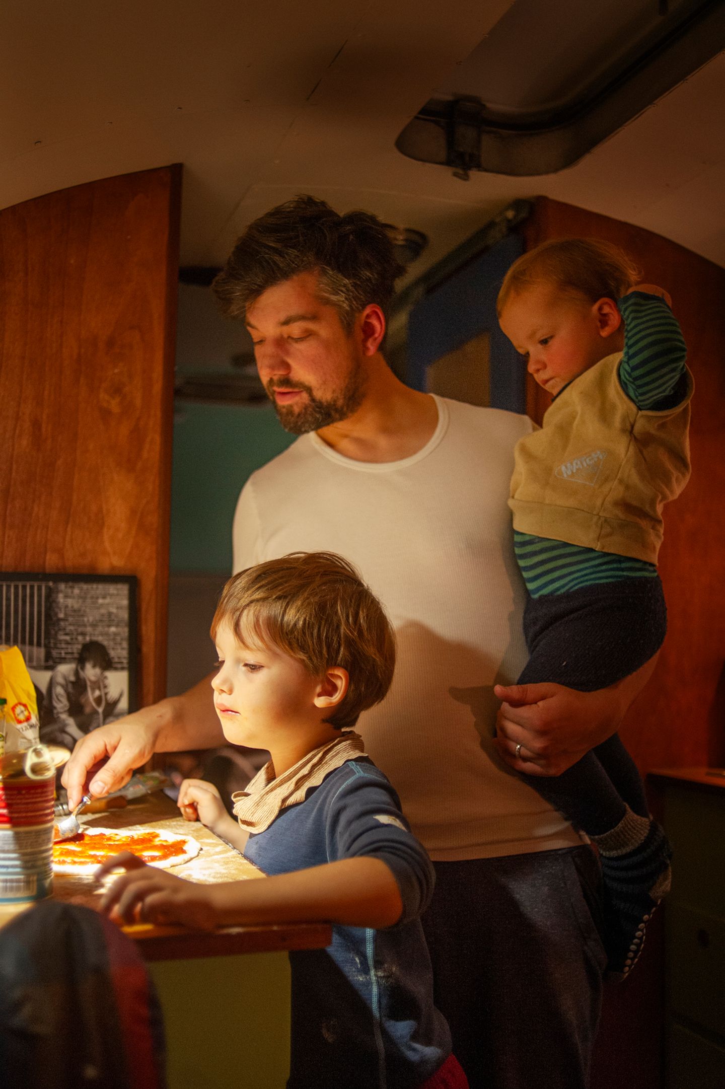 Der Vater steht mit seinen zwei Söhnen in der Küche des Airstreams und bereitet Pizza zu