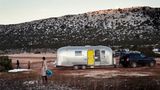 Vor dem geparkten Airstream spielen die beiden Jungs in den letzten Schneeresten. Im Hintergrund karge Berge.