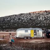 Vor dem geparkten Airstream spielen die beiden Jungs in den letzten Schneeresten. Im Hintergrund karge Berge.