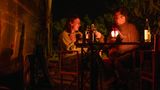 Die Eltern sitzen abends bei einem Glas vor dem Airstream zusammen und unterhalten sich im Schein einer Laterne