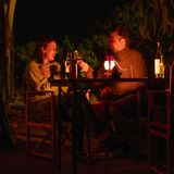 Die Eltern sitzen abends bei einem Glas vor dem Airstream zusammen und unterhalten sich im Schein einer Laterne