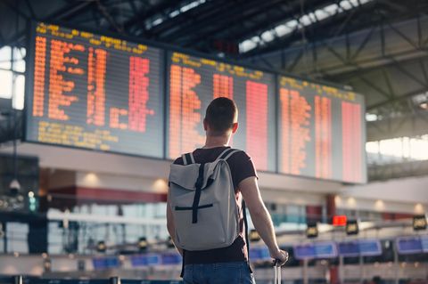 Junger Mann mit Handgepäck am Flughafen