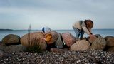 Die beiden Jungs spielen auf einigen großen Steinen am Strand