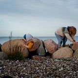 Die beiden Jungs spielen auf einigen großen Steinen am Strand