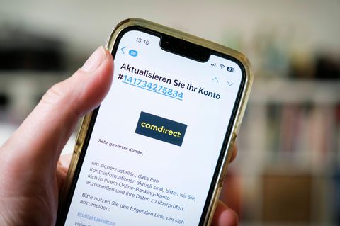 Ein Handy wird in der Hand gehalten. Darauf eine offene Phishing-Mail, die vorgibt von der Comdirect zu stammen.