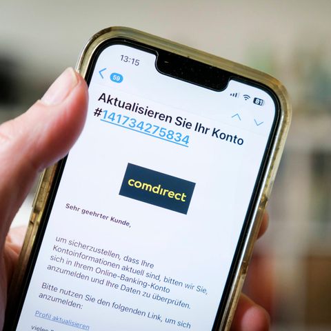 Ein Handy wird in der Hand gehalten. Darauf eine offene Phishing-Mail, die vorgibt von der Comdirect zu stammen.