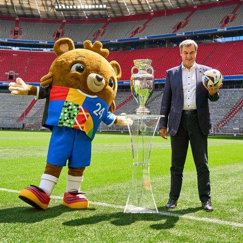 Markus Söder steht im Stadion mit dem EM-Maskottchen