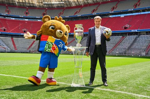 Markus Söder steht im Stadion mit dem EM-Maskottchen