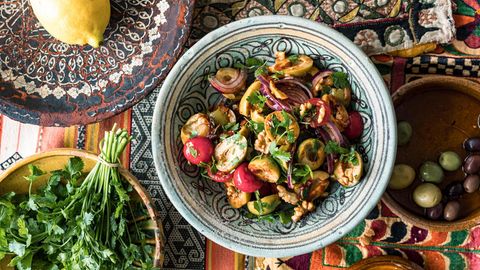 Olivensalat angerichtet neben Zitrone und Kräutern