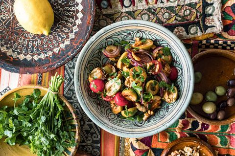 Olivensalat angerichtet neben Zitrone und Kräutern