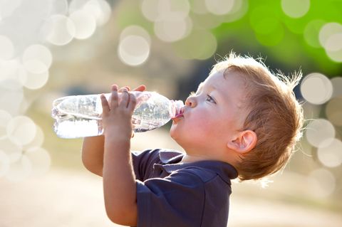 Chemikalien im Trinkwasser: Kleiner Junge trinkt aus Wasserflasche