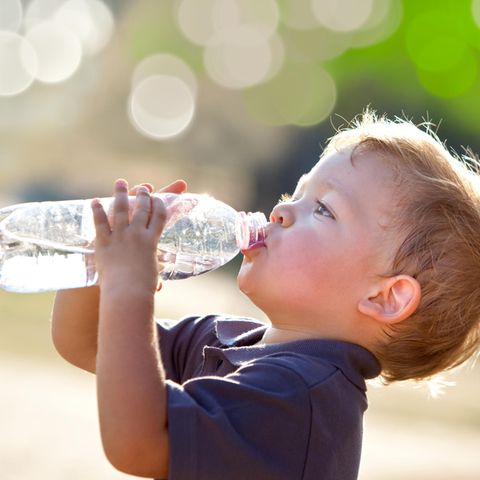 Chemikalien im Trinkwasser: Kleiner Junge trinkt aus Wasserflasche