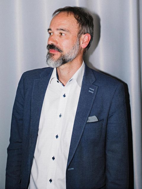 Porträt von Stefan Pohlmann vor einem hellblauen Vorhang