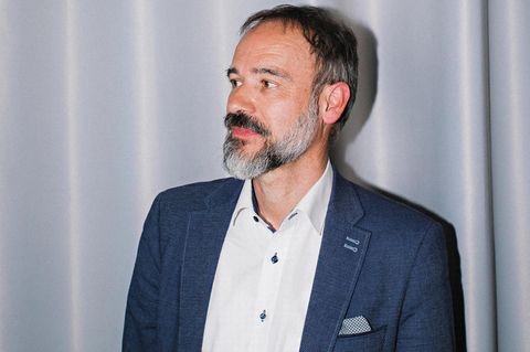 Porträt von Stefan Pohlmann vor einem hellblauen Vorhang
