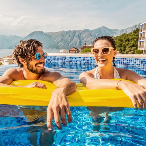 Pauschalurlaub: Paar treibt auf einer Luftmatratze im Pool am Urlaubsort