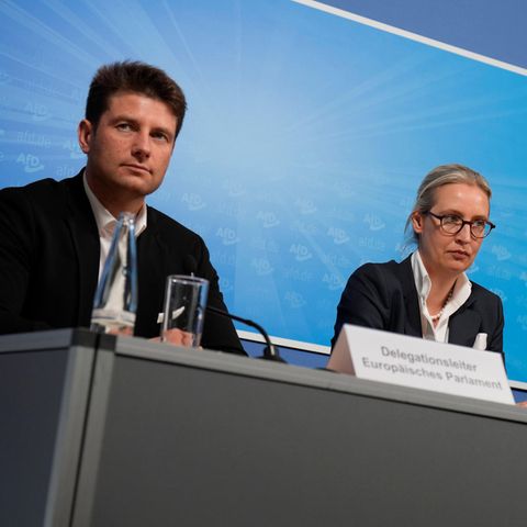 René Aust, Alice Weidel und Tino Chrupalla sitzen bei einer Pressekonferenz vor AfD-Logo