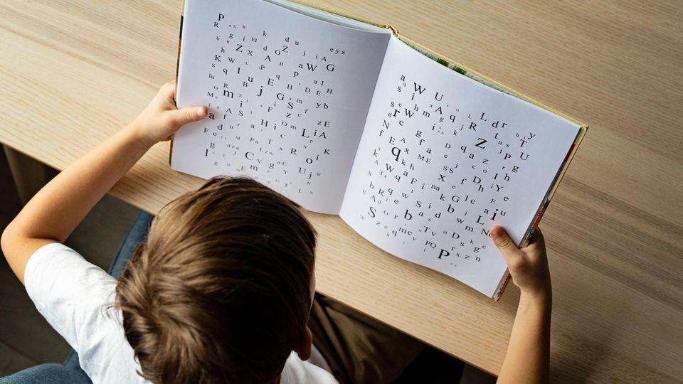 Lernstörung: Ein Kind schaut in ein Buch mit Buchstaben