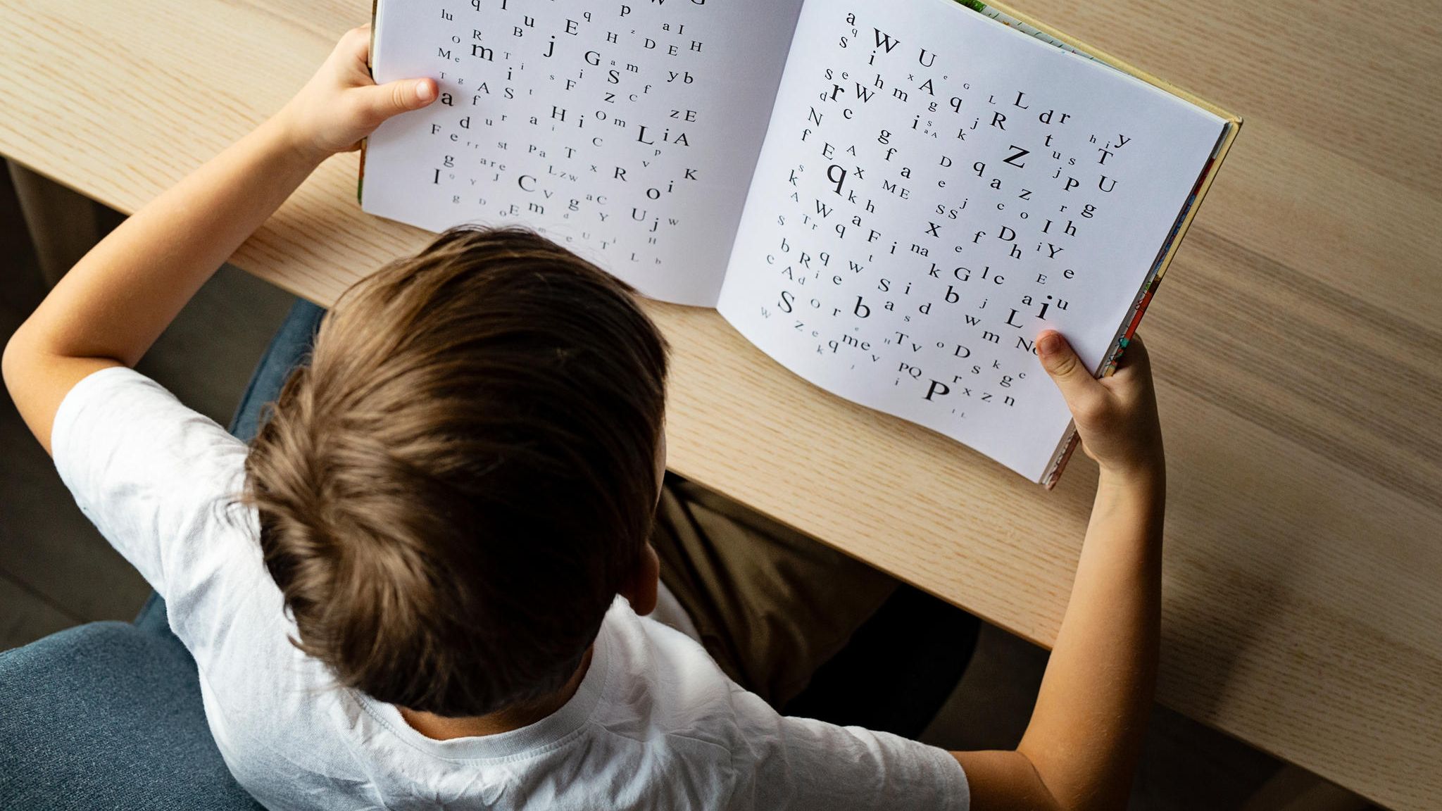 Lernstörung: Ein Kind schaut in ein Buch mit Buchstaben