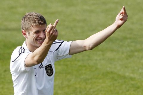 Thomas Müller zeigt auf dem Trainingsplatz im DFB-Dress lächelnd jemandem beide Mittelfinger