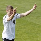 Thomas Müller zeigt auf dem Trainingsplatz im DFB-Dress lächelnd jemandem beide Mittelfinger