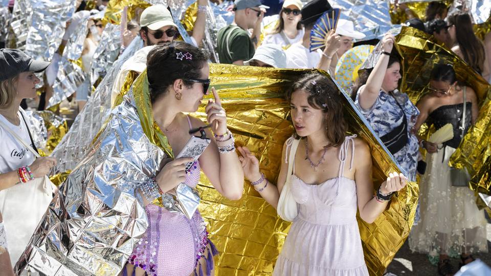 Schwitzen für die Königin: Schweizer "Swifties" schützten sich mit Rettungsdecken vor den Sonnenstrahlen, als sie in Zürich auf das Konzert der US-Sängerin warten. 