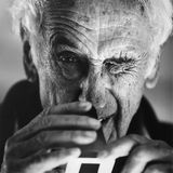 Thomas Hoepker kneift ein Auge zusammen und schaut eine Aufnahme an