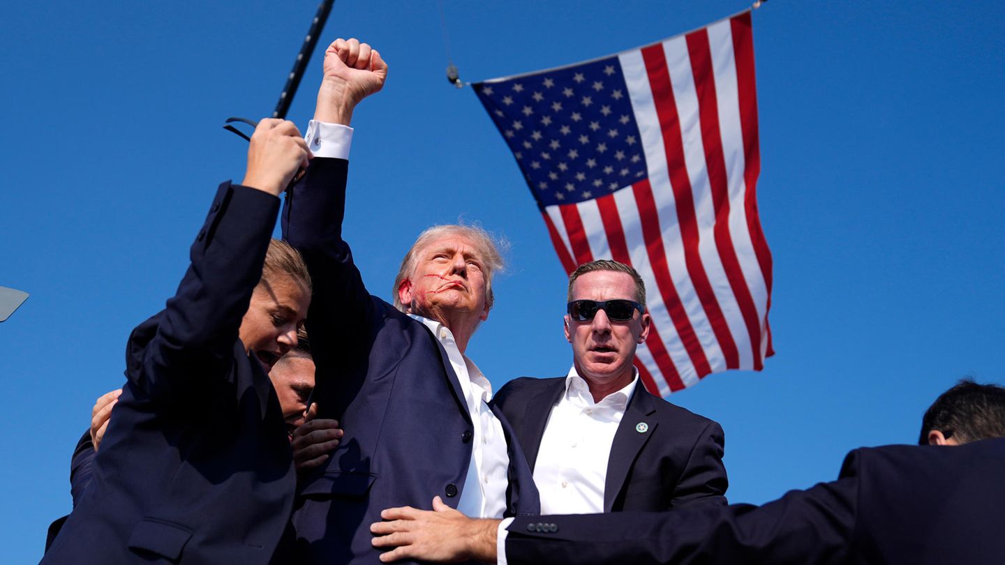 Das Team des Secret Service umringt ihn, richtet ihn auf und will ihn von der Bühne bringen. Dann hört man auf Videoaufnahmen, wie Trump innehält: "Wartet", sagt er und ruft dann "Kämpft, kämpft" während er die Faust in die Höhe reckt