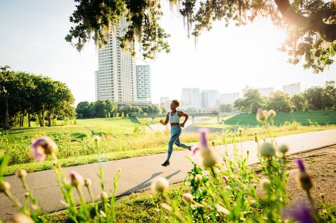 Eine Joggerin läuft im Sommer über einen Weg in der Natur