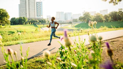 Eine Joggerin läuft im Sommer über einen Weg in der Natur