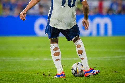 Der Fußballprofi Jude Bellingham spielt einen Ball und trägt zerschnittene Stutzen.