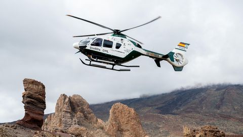 Ein Hubschrauber der Guardia Civil fliegt tief über einer felsigen Landschaft auf Teneriffa