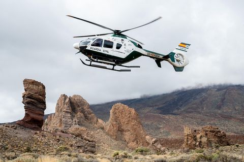 Ein Hubschrauber der Guardia Civil fliegt tief über einer felsigen Landschaft auf Teneriffa