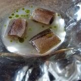 In einer Glasschale werden drei Stücke vom Kapelan serviert, ein Fisch aus der Familie der Stinte, fermentiert im Fruchtsaft der Stachelbeere.